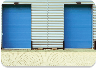 Two large, closed blue roller doors on a building with a corrugated metal wall.
